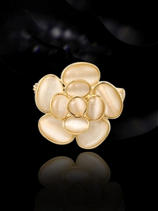 Gros plan d'une broche camélia avec pierres d'opale et bordure dorée sur fond miroir