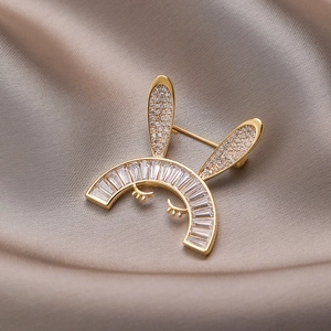 Broche lapin dorée mignonne avec zircons cubiques sur fond de soie couleur champagne