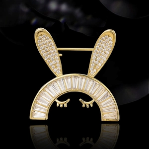 Broche lapin dorée sertie de zircons cubiques sur fond noir avec effet miroir