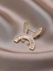 Détail d'une jolie broche lapin dorée avec cristaux sur un tissu en soie champagne