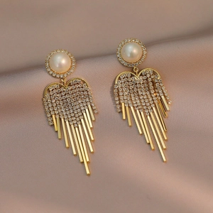 Elegant gold heart tassel earrings with pearls and rhinestones on silk background