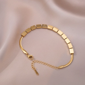 Bracelet en acier inoxydable doré avec gravure LOVE posé sur un tissu en soie rose