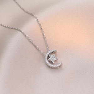 Elegante Halskette mit Stern und Mond Anhänger und Zirkonia auf rosa Seidenhintergrund