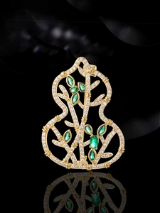 Detailed view of hollow gourd brooch with gold frame, white zircons and green gems