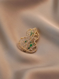 Detailed view of hollow gourd brooch with gold frame, inlaid zircons and green crystals