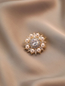 Gros plan d'une broche florale avec perles blanches, cristal central et strass brillants