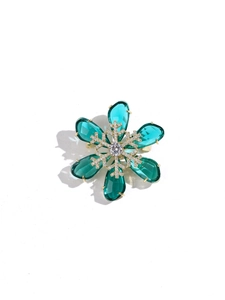 Close-up of snowflake brooch with emerald green teardrop stones and sparkling crystals