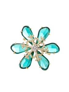 Detailed close-up of a golden snowflake brooch with emerald green teardrop crystals