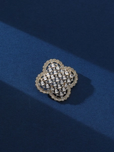 Détail d'une broche fleur à quatre feuilles dorée sertie de zircons cubiques brillants