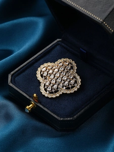 Gros plan d'une broche trèfle dorée avec zircons sur un écrin de velours