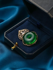 Detalle de un broche vintage con jade verde y perlas en caja de terciopelo azul