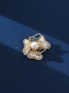 Détail de la broche fleur en nacre avec perle blanche, cristaux colorés et bords dorés