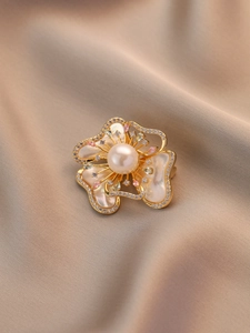 Vue détaillée d'une broche fleur avec perle et pétales de nacre sur de la soie