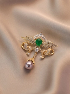 Detail der Vintage-Engelsflügel-Brosche mit grünem Edelstein, Quasten und Perle auf Seide