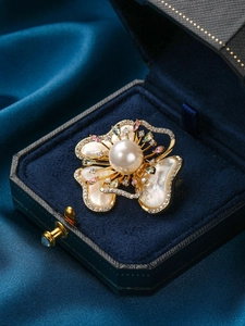 Vue détaillée d'une broche fleur en nacre avec perle et cristaux dans un écrin en velours