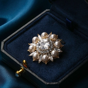 Élégante broche dorée en perles avec cristal sur une boîte à bijoux en velours bleu