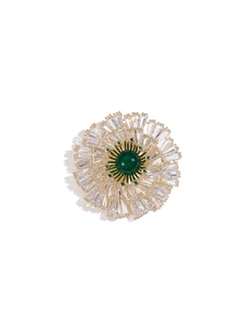 Close-up of a golden radial floral brooch with a green center stone and crystals