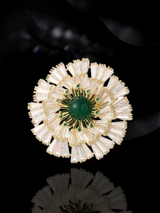 Macro shot of radial floral brooch with emerald center and tiered zircon petals