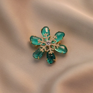 Elegant snowflake brooch with emerald green teardrop crystals and gold plating