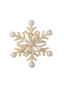 Detailed close-up of golden snowflake brooch featuring inlaid pearls and clear rhinestones