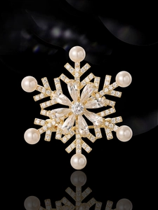 Macro shot of gold snowflake brooch with sparkling cubic zirconia and six elegant pearls