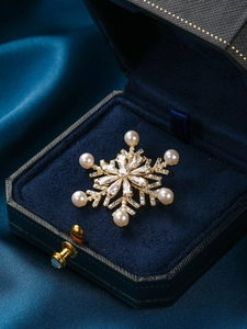 Close-up of a golden snowflake brooch with pearls and zircons in a blue velvet box