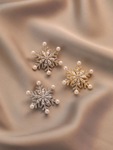 Close-up of gold and silver snowflake brooches with zircon crystals and pearls