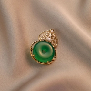 Broche de jade vintage en forma de calabaza con marco dorado sobre raso champán