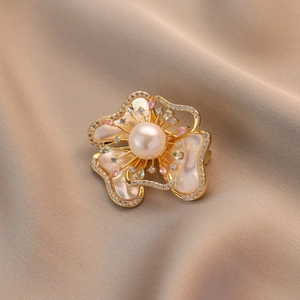 Élégante broche fleur en nacre avec perle et cristaux sur fond de soie douce
