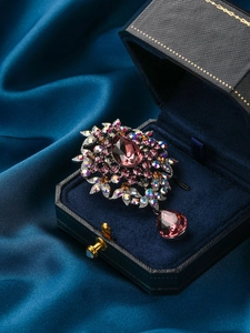 Detailed close-up of a vintage brooch with pink pear-shaped gem in a premium blue gift box
