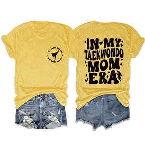 Detail view of yellow T-shirt with 'IN MY TAEKWONDO MOM ERA' retro print and denim shorts