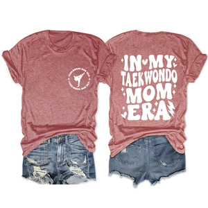 Flat lay of red Taekwondo Mom Era T-shirt with distressed denim shorts on white background