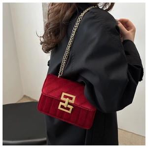 Dettaglio della borsa trapuntata in velluto rosso con catena d'oro indossata da modella