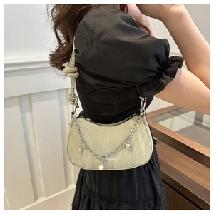 Détail du sac froncé vert clair avec chaîne argentée et pendentif cœur en perle