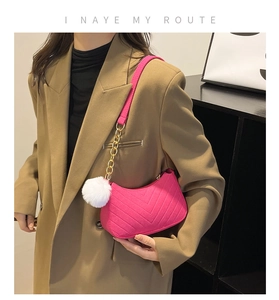 Détail d'un sac bandoulière matelassé rose avec chaîne dorée et pompon blanc