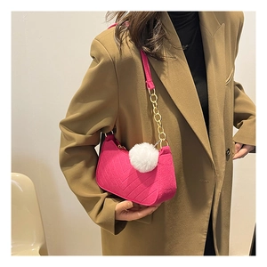 Détail du sac porté épaule en feutre rose avec chaîne dorée et pompon blanc décoratif