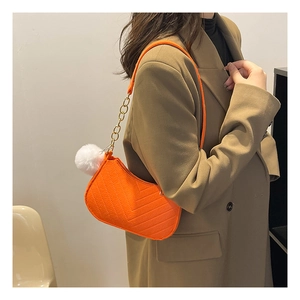 Détail du sac à bandoulière matelassé orange avec chaîne dorée et pompon en fausse fourrure