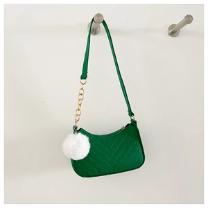 Détail du sac baguette vert en feutre avec matelassage en V, chaîne dorée et pompon blanc