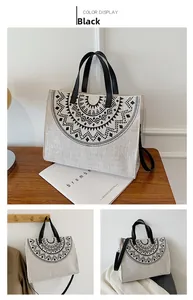 Detail der cremefarbenen Canvas-Tasche mit schwarzem Print und Ledergriffen