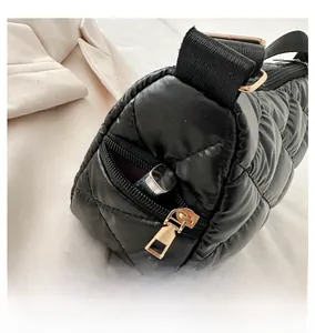 Détail de la poche latérale avec zip doré sur un sac bandoulière matelassé noir