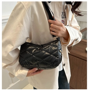 Détail de la texture matelassée du sac bouffant noir et de la bandoulière sur le modèle