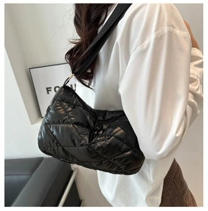Détail d'un sac matelassé noir en nylon brillant montrant la bandoulière et la texture