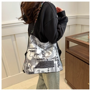 Detail view of large graffiti print tote bag with colorful lettered strap on model shoulder