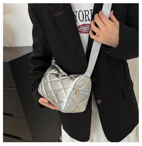 Détail du sac bandoulière argenté matelassé avec reflets et finitions dorées