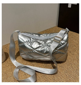 Détail d'un sac bandoulière argenté matelassé avec sangle en nylon et boucle métallique