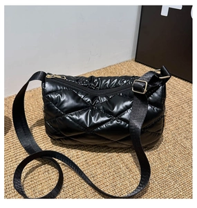 Détail d'un sac matelassé noir brillant avec des finitions et une fermeture éclair dorée