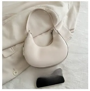 Detail of minimalist cream half-moon bag with metallic buckle and leather texture