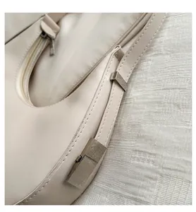 Detailed close-up of cream crescent bag with silver zipper and matte leather texture