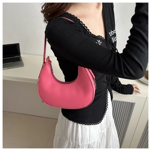 Pink matte leather saddle bag worn by model, showing the minimalist half-moon shape