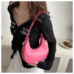 Detail of pink crescent bag showing leather texture and silver buckle on a shoulder strap